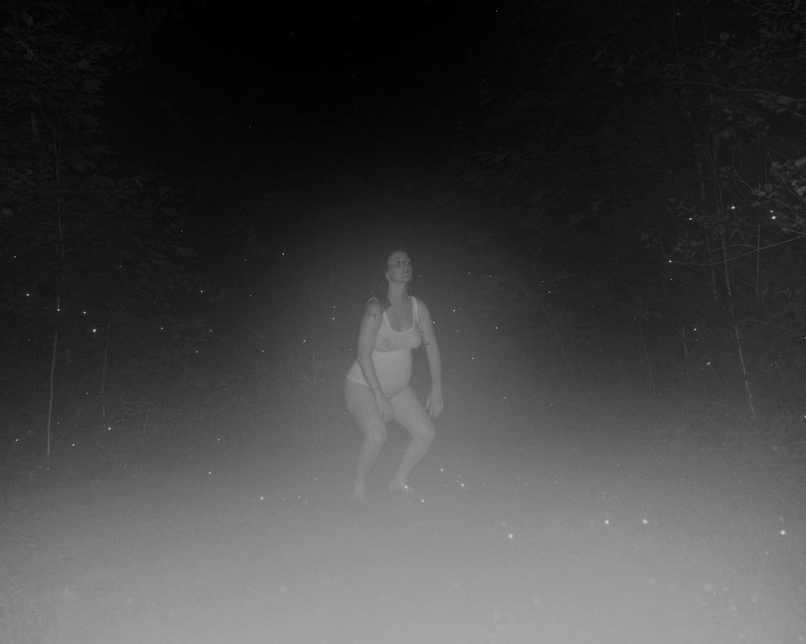 A pregnant person outside at night